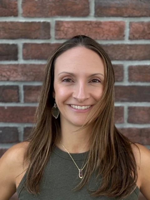 Portrait of Aimee Brown, Roamler's Head of Delivery, smiling in front of a brick wall
